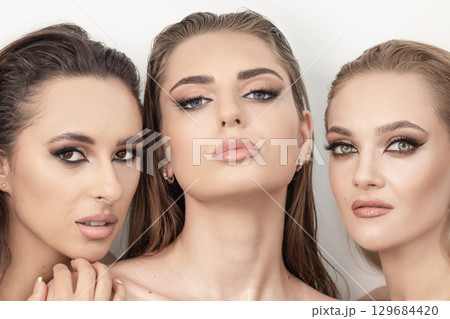 Three beautiful women with smokey make-up and wet hair studio portrait Three beautiful women with smokey make-up and wet hair studio portrait 129684420