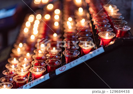 Rows of lit red votive candles in a dimly lit setting in a church in Vienna, Austria Rows of lit red votive candles in a dimly lit setting in a church in Vienna, Austria 129684438