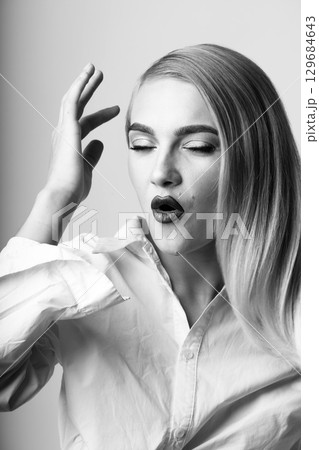 Beautiful blonde woman with long hair making O shape with lips close-up studio portrait 129684643