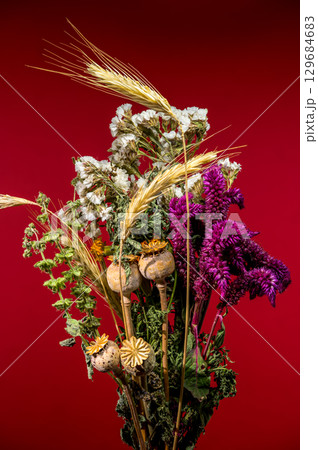 Dried Flower and Wheat Bouquet on Vibrant Red Surface Dried Flower and Wheat Bouquet on Vibrant Red Surface 129684683