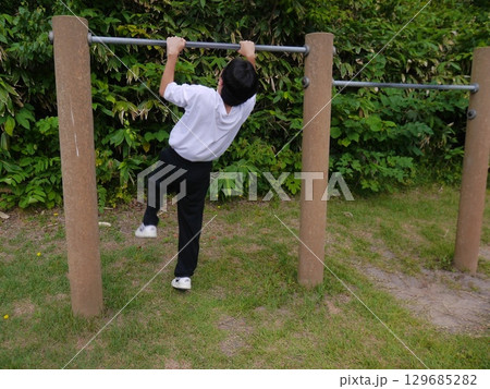 鉄棒をする男性(後ろ姿) 129685282
