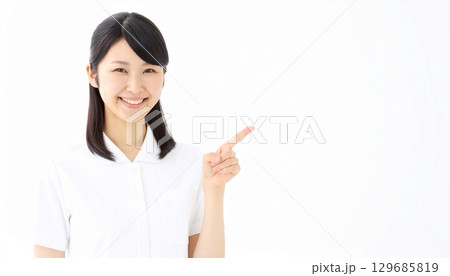 白背景に私服を着て指差す笑顔の若い女性の説明している人物写真 129685819
