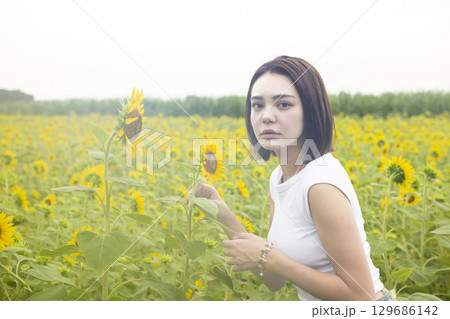 ひまわり畑を散歩する女性 129686142