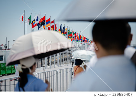 国旗 暑い中日傘をさして歩く人々 国旗 暑い中日傘をさして歩く人々 129686407