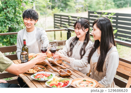 ウッドデッキでホームパーティー・グランピングする若いアジア人カップル 129686620
