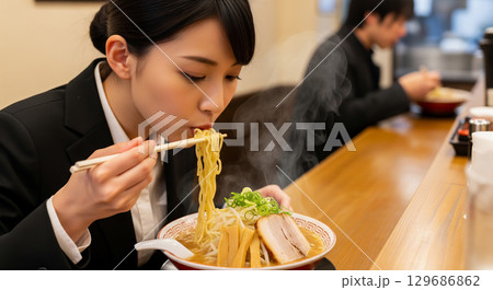 ラーメン屋でラーメンを食べる女性 129686862