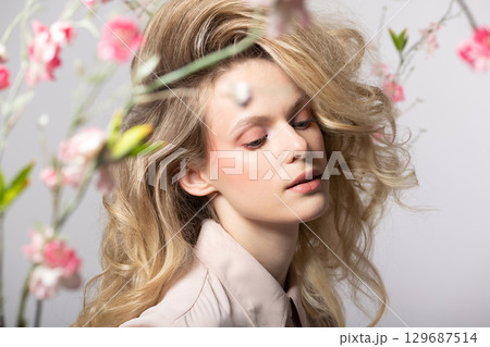 Beautiful woman with big wavy hair and flowers studio portrait 129687514