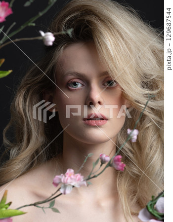 Beautiful woman with big wavy hair and flowers studio portrait 129687544