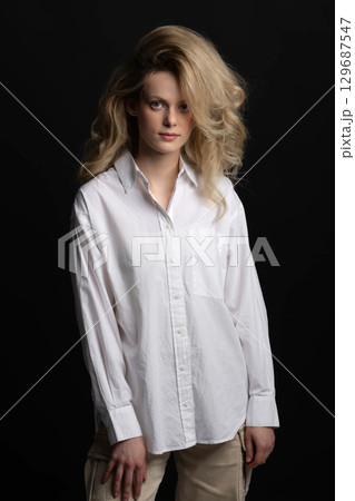 Beautiful woman with big wavy hair and white shirt studio portrait 129687547