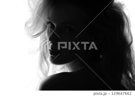 Beautiful woman with big wavy hair black and white studio portrait in bright background Beautiful woman with big wavy hair black and white studio portrait in bright background 129687662