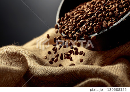 Freshly roasted coffee beans are poured into a bag. Freshly roasted coffee beans are poured into a bag. 129688323