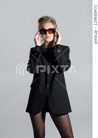 Beautiful woman with black suit and sunglasses studio portrait portrait 129688431