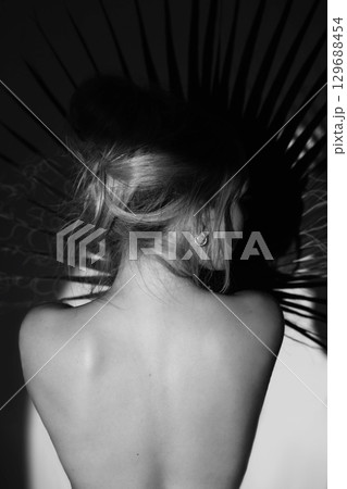 Beautiful woman with naked back and palm leaf black and white studio portrait Beautiful woman with naked back and palm leaf black and white studio portrait 129688454