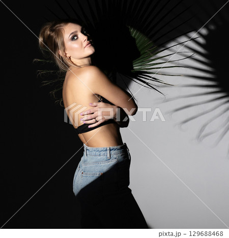 Studio portrait of beautiful woman hugging herself and illuminated with bright studio light Studio portrait of beautiful woman hugging herself and illuminated with bright studio light 129688468