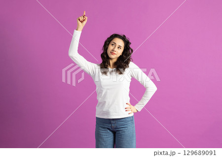 Beautiful woman pointing finger up and looking with suspicious facial expression Beautiful woman pointing finger up and looking with suspicious facial expression 129689091