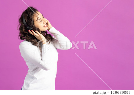 Woman with headphones on pink background 129689095