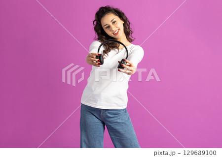 Woman with headphones on pink background 129689100