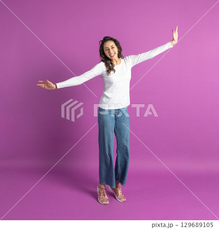 Positive young girl jumping in air against purple background Positive young girl jumping in air against purple background 129689105