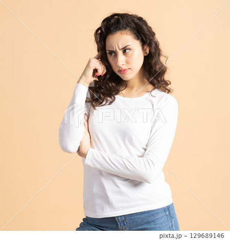 Thoughtful woman portrait on beige background Thoughtful woman portrait on beige background 129689146