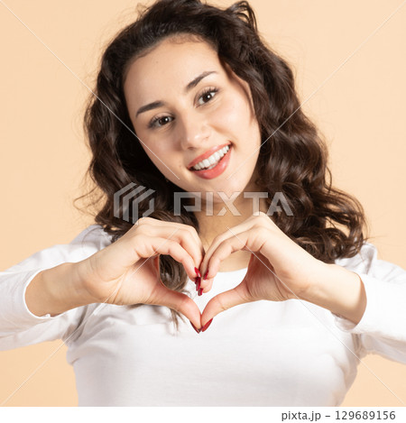 Beautiful woman showing fingers heart sign Beautiful woman showing fingers heart sign 129689156