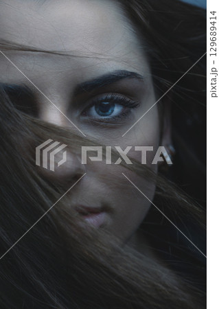 Beautiful woman with blue eyes cover her face with hair Beautiful woman with blue eyes cover her face with hair 129689414