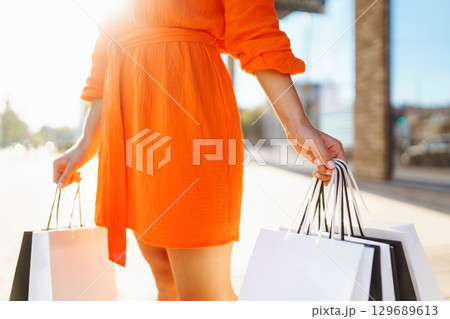 Young woman with shopping bags near mall. Purchases, shopping, lifestyle, sale concept. 129689613