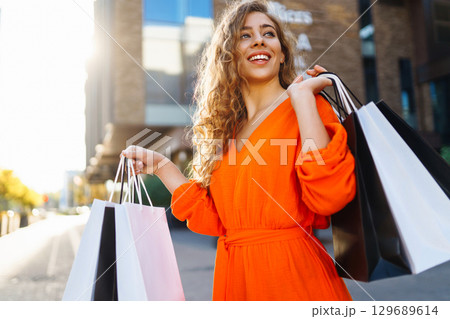 Young woman with shopping bags near mall. Purchases, shopping, lifestyle, sale concept. 129689614