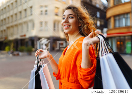 Young woman with shopping bags near mall. Purchases, shopping, lifestyle, sale concept. 129689615