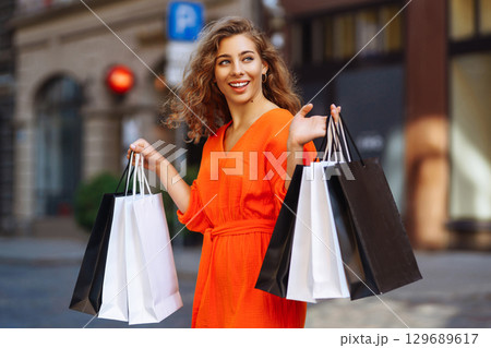 Young woman with shopping bags near mall. Purchases, shopping, lifestyle, sale concept. 129689617