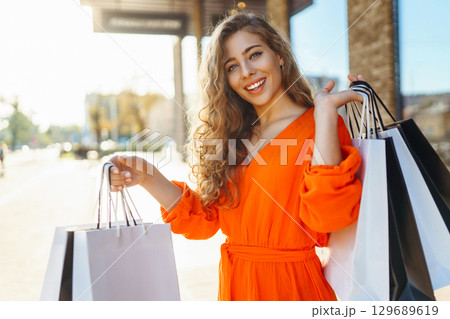 Young woman with shopping bags near mall. Purchases, shopping, lifestyle, sale concept. 129689619