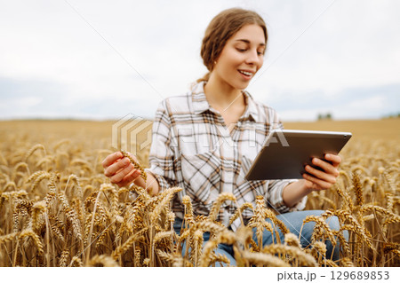 Woman agronomist in a field with a tablet checks the growth of the crop. New harvest concept. 129689853