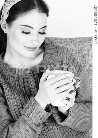Beautiful woman with sweater holding cup in her hands Beautiful woman with sweater holding cup in her hands 129689887
