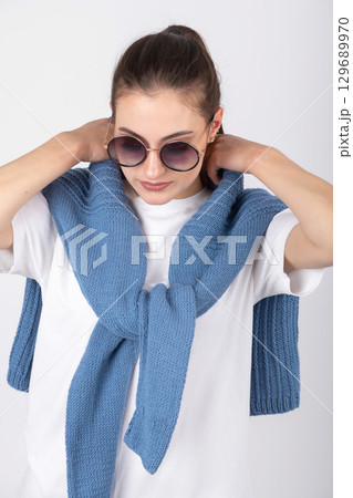 Woman with sunglasses and blue sweater on her shoulders 129689970