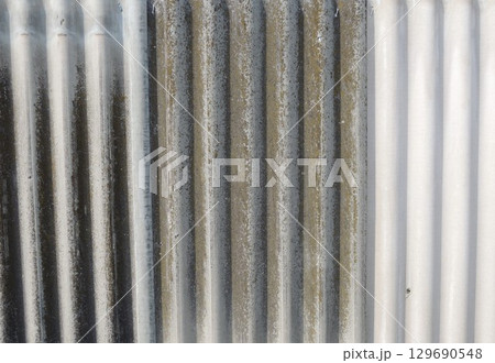 corrugated surface of gray covering material with a gradient of gray color from dark to light shade, corrugated slate in a vertical position, use of covering material for construction 129690548