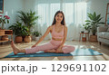 明るいリビングでヨガを楽しむ若い女性 129691102