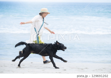 犬と海辺を走る人 アクティブな飼い主のイメージ 犬と海辺を走る人 アクティブな飼い主のイメージ 129691202