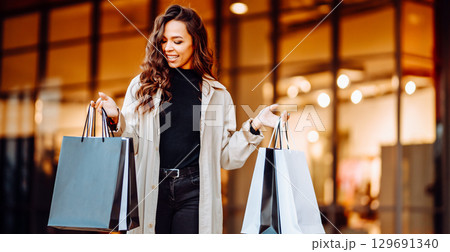 Young woman with shopping bags near mall. Spring Style. Consumerism, purchases, shopping, lifestyle Young woman with shopping bags near mall. Spring Style. Consumerism, purchases, shopping, lifestyle 129691340