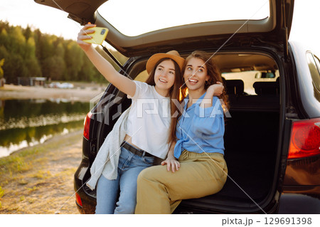 Smiling young woman have fun in the back seat of a car while traveling. Active lifestyle. 129691398