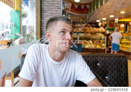 Man in a white shirt is sitting at a table in a restaurant Man in a white shirt is sitting at a table in a restaurant 129691438