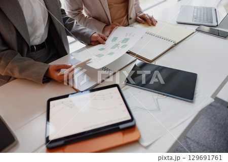 A Business Meeting Utilizing Digital Devices, Papers, and Various Documents for Efficiency 129691761