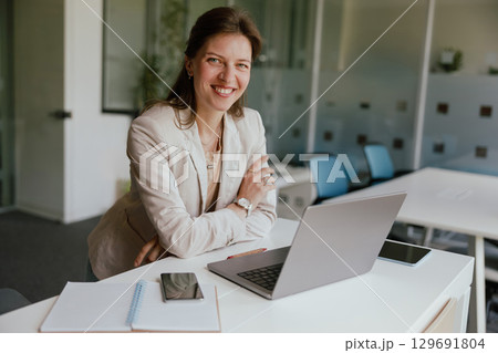 A confident businesswoman is diligently working in a modern, creative office environment 129691804