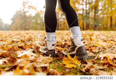 Female legs in boots walking through fallen trees in autumn park. Nature, travel concept. 129693282
