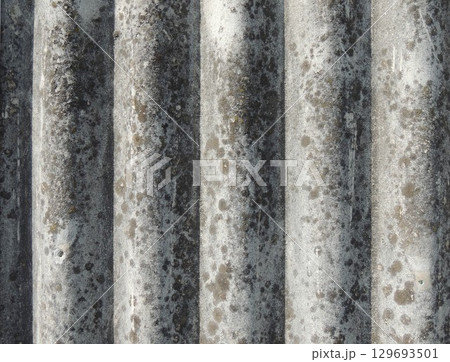 slate close-up with textured wavy surface, curved smooth relief, gray color with abstract spots, fragment of roof covering material in aged condition 129693501