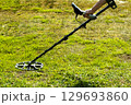 A man walks through a field with a metal detector in search of treasure 129693860
