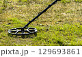 A man walks through a field with a metal detector in search of treasure 129693861