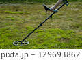 A man walks through a field with a metal detector in search of treasure 129693862