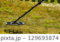 a man walks through a field with a metal detector 129693874