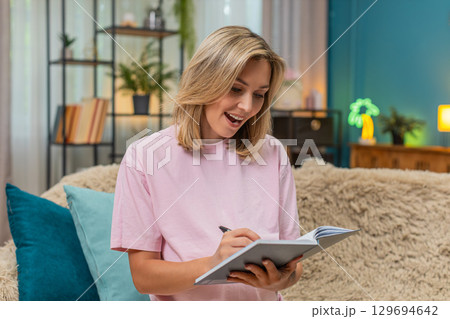 Pregnant woman lifts finger eureka idea writing baby name in notebook smiling new inspiration joyful Pregnant woman lifts finger eureka idea writing baby name in notebook smiling new inspiration joyful 129694642