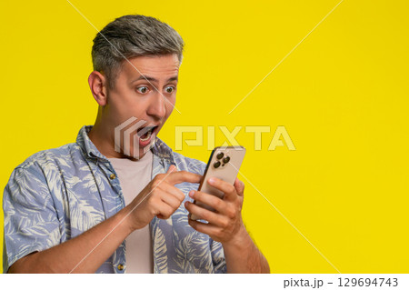 Man scrolling smartphone suddenly shocked with wide eyes open mouth surprised by unexpected news Man scrolling smartphone suddenly shocked with wide eyes open mouth surprised by unexpected news 129694743