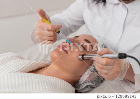 Injection-free mesotherapy or electroporation, beautician makes woman face therapy in clinic salon 129695143